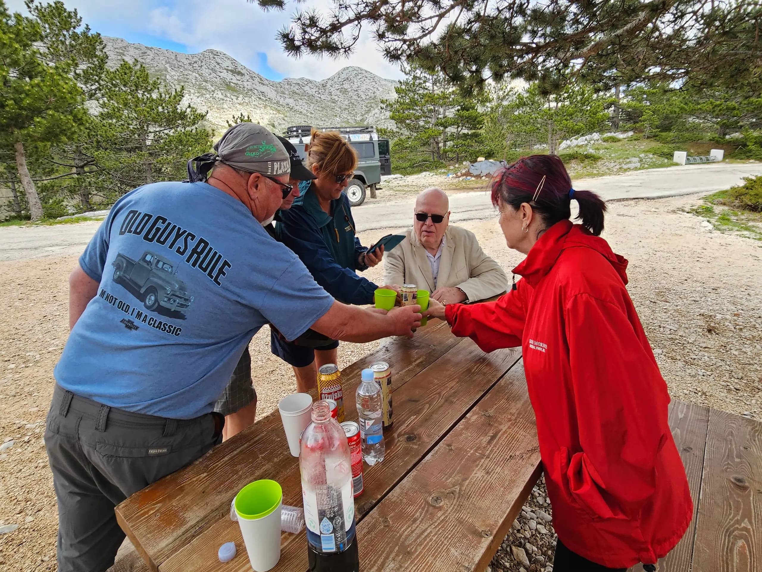 Grupa turista uživa u pikniku na planini Biokovo s Land Rover Defenderom u pozadini