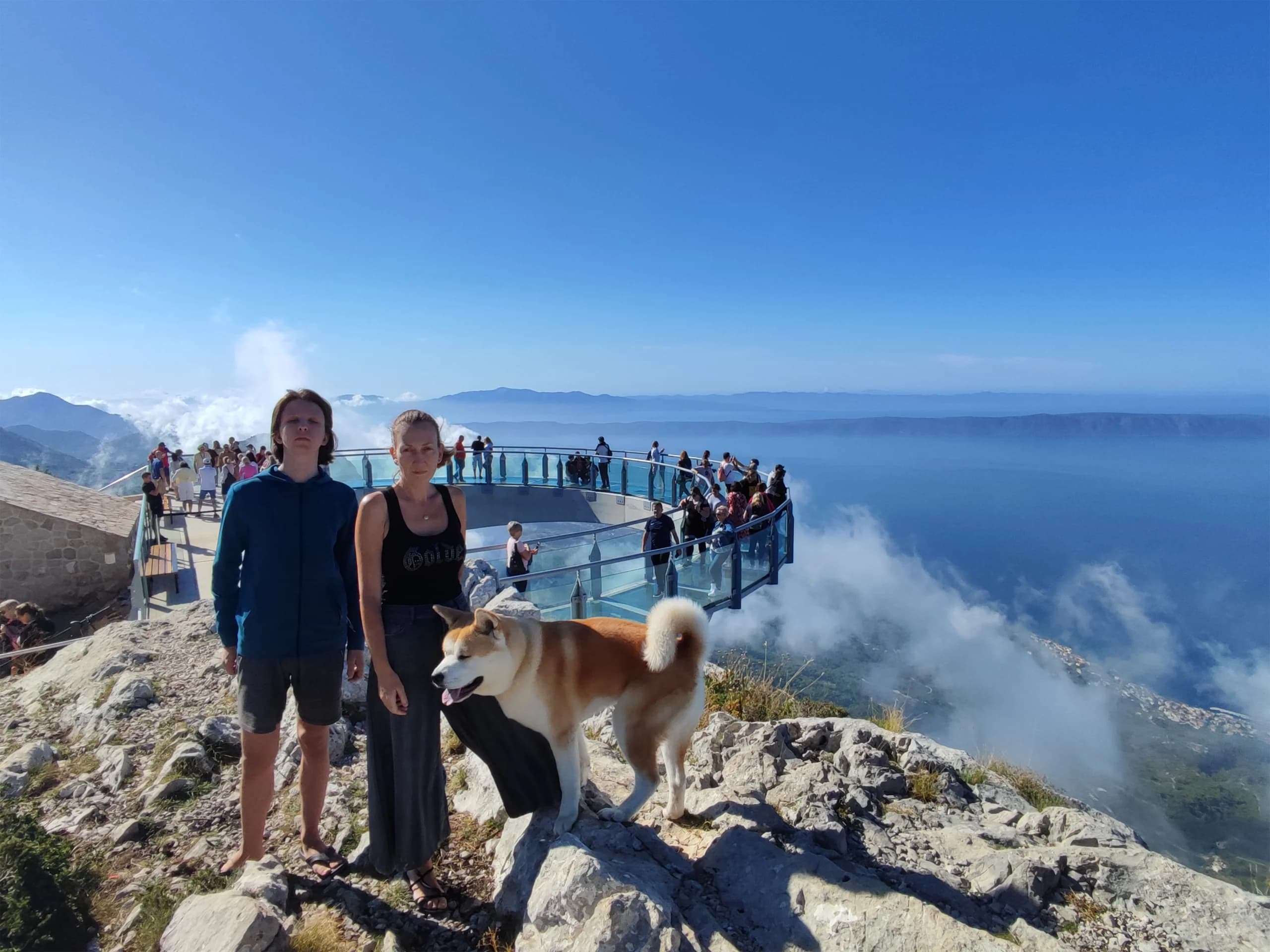 Turisti i pas na staklenoj platformi Skywalk s prostranim pogledom na more i obalu